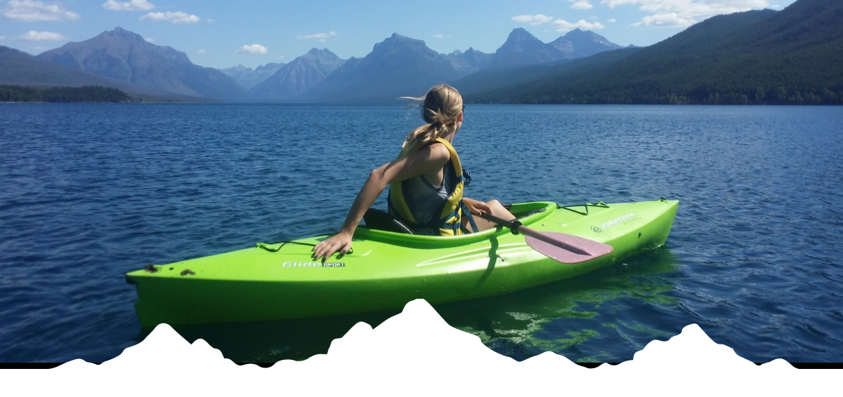 Image: A woman in a green kayak on a mountain lake. 