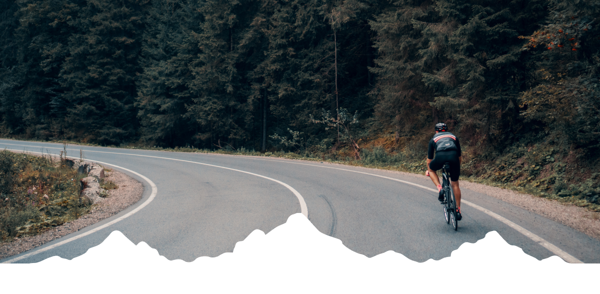 A cyclist on an empty road in the woods