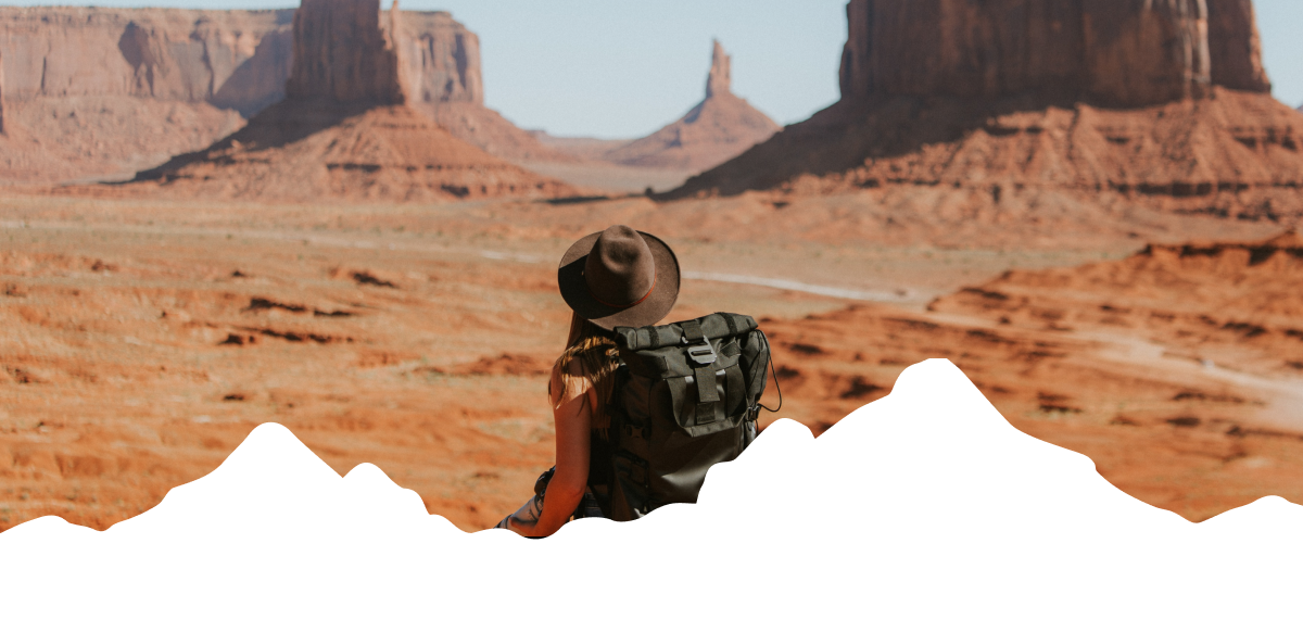 Image: a woman hiking in the desert with a big hat. 